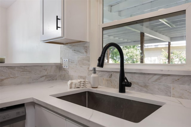 3813 Surrey Dr, Orlando, FL 32812 - kitchen view of a sink, white cabinets, decorative backsplash, dishwasher, and light stone countertops