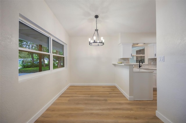 3813 Surrey Dr, Orlando, FL 32812 - unfurnished dining area featuring a chandelier, light wood-type flooring, baseboards, a sink, and a textured wall