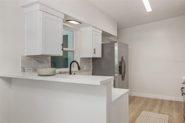 3813 Surrey Dr, Orlando, FL 32812 - kitchen with a sink, backsplash, light wood-style floors, white cabinets, and stainless steel refrigerator with ice dispenser