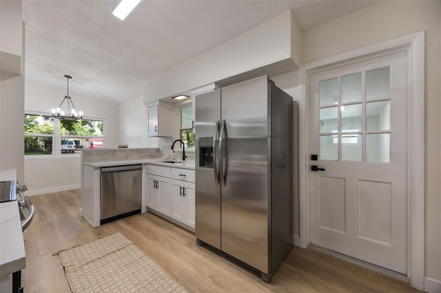 3813 Surrey Dr, Orlando, FL 32812 - kitchen featuring stainless steel appliances, a chandelier, a sink, white cabinets, and light wood-type flooring
