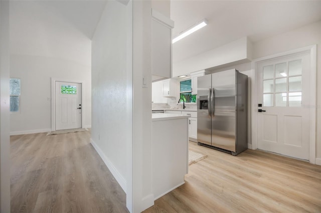 3813 Surrey Dr, Orlando, FL 32812 - kitchen with stainless steel refrigerator with ice dispenser, a sink, light wood-style floors, light countertops, and white cabinetry