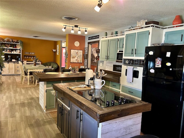 103 Inglis Way, Wauchula, FL 33873 - kitchen with black appliances, wooden counters, green cabinetry, a kitchen island, and a textured ceiling