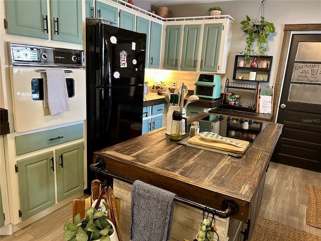 103 Inglis Way, Wauchula, FL 33873 - kitchen with wall oven, green cabinets, freestanding refrigerator, light wood-type flooring, and light countertops