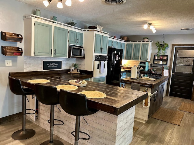 103 Inglis Way, Wauchula, FL 33873 - kitchen featuring freestanding refrigerator, oven, wood finished floors, stainless steel microwave, and a textured ceiling