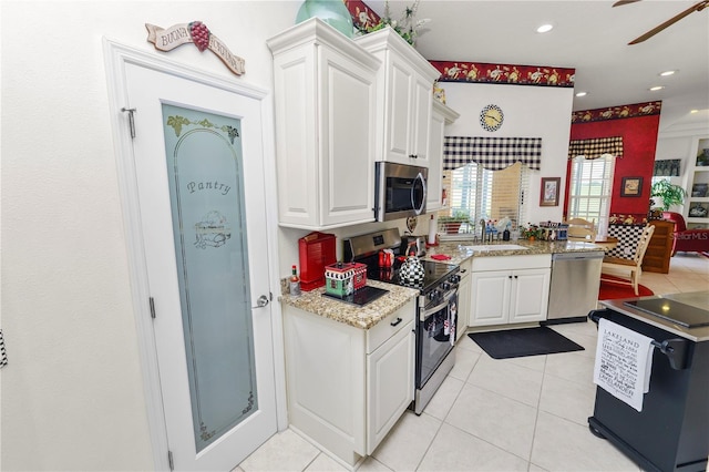 2936 Grasslands Dr, Lakeland, FL 33803 - kitchen featuring stainless steel appliances, a sink, white cabinets, light tile patterned floors, and a ceiling fan