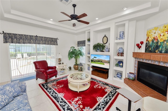 2936 Grasslands Dr, Lakeland, FL 33803 - living area featuring a raised ceiling, built in shelves, a ceiling fan, tile patterned flooring, and a tile fireplace