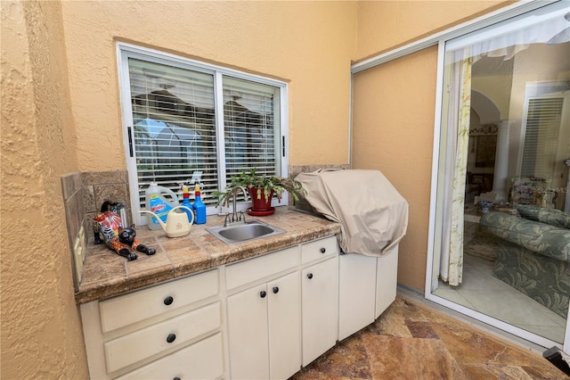 2936 Grasslands Dr, Lakeland, FL 33803 - interior space featuring a sink, a textured wall, stone finish flooring, and white cabinetry