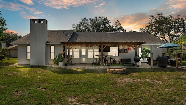 1423 Ridgegreen Loop N, Lakeland, FL 33809 - back of house at dusk featuring an outdoor fire pit, a chimney, a patio area, and a lawn