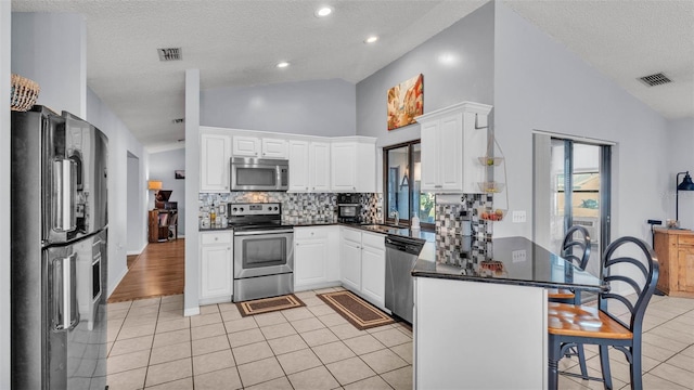 1423 Ridgegreen Loop N, Lakeland, FL 33809 - kitchen with appliances with stainless steel finishes, a peninsula, a breakfast bar area, a textured ceiling, and backsplash