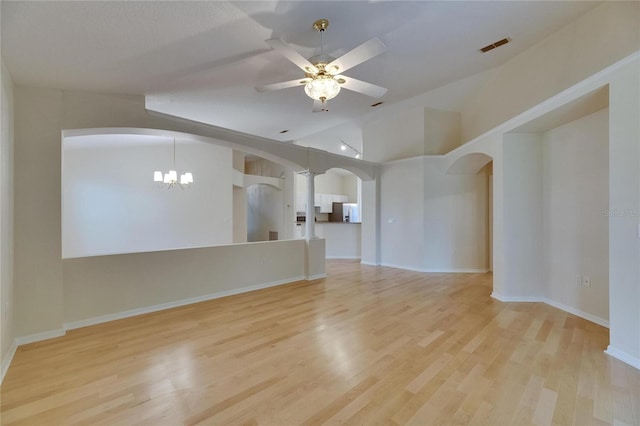 1003 Clearpointe Way, Lakeland, FL 33813 - unfurnished living room with arched walkways, light wood finished floors, ceiling fan, a chandelier, and vaulted ceiling