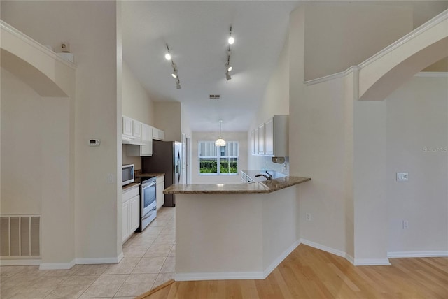 1003 Clearpointe Way, Lakeland, FL 33813 - kitchen featuring stainless steel appliances, arched walkways, white cabinets, a peninsula, and under cabinet range hood
