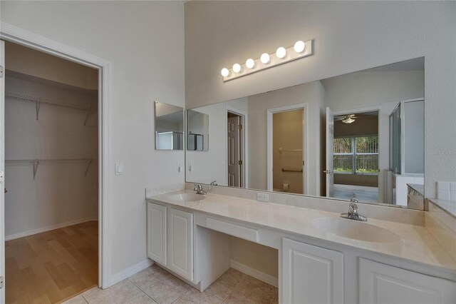 1003 Clearpointe Way, Lakeland, FL 33813 - bathroom featuring double vanity, a walk in closet, ceiling fan, tile patterned floors, and baseboards