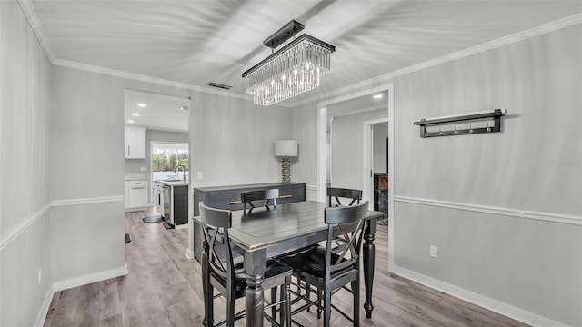 4825 Foxrun, Lakeland, FL 33813 - dining space with crown molding, a chandelier, light wood-style flooring, and baseboards