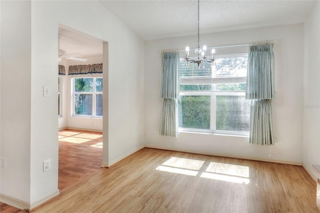 6065 Magpie Dr, Lakeland, FL 33809 - unfurnished dining area with wood finished floors, a chandelier, baseboards, a textured ceiling, and a ceiling fan