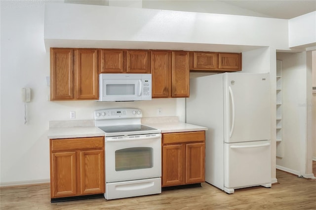 6065 Magpie Dr, Lakeland, FL 33809 - kitchen with white appliances, light countertops, light wood-style floors, and brown cabinetry
