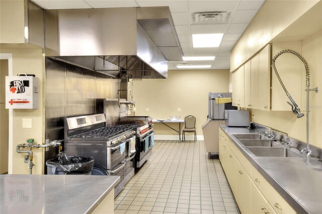 6065 Magpie Dr, Lakeland, FL 33809 - kitchen with stainless steel countertops, range with two ovens, light tile patterned floors, a drop ceiling, and a sink