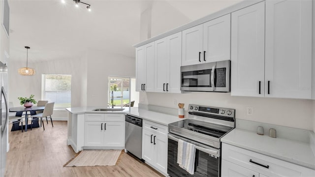 5458 Oakford Dr, Lakeland, FL 33812 - kitchen with stainless steel appliances, a sink, a peninsula, light countertops, and light wood-style flooring