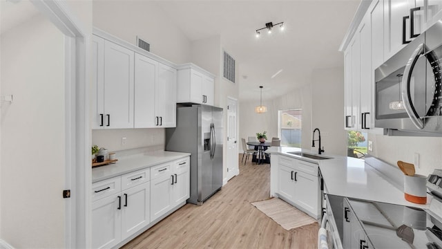 5458 Oakford Dr, Lakeland, FL 33812 - kitchen featuring stainless steel appliances, a sink, white cabinetry, light wood-style floors, and light countertops