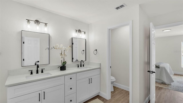 5458 Oakford Dr, Lakeland, FL 33812 - ensuite bathroom featuring wood finished floors, double vanity, toilet, and baseboards