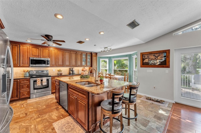 5108 Waterwood Dr, Bartow, FL 33830 - kitchen with stainless steel appliances, a sink, a textured ceiling, brown cabinets, and plenty of natural light