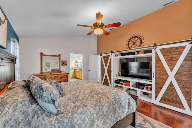 5108 Waterwood Dr, Bartow, FL 33830 - bedroom with wood finished floors, vaulted ceiling, a barn door, a ceiling fan, and connected bathroom