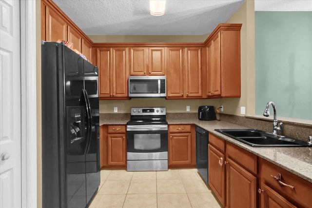2061 Crestdale Ln Unit 60, Lake Mary, FL 32746 - kitchen with black appliances, a sink, light tile patterned floors, brown cabinetry, and a textured ceiling