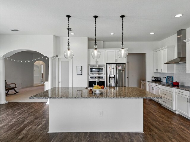 1547 Cordgrass Way, Lakeland, FL 33813 - kitchen with appliances with stainless steel finishes, arched walkways, wall chimney range hood, a kitchen island, and ornate columns