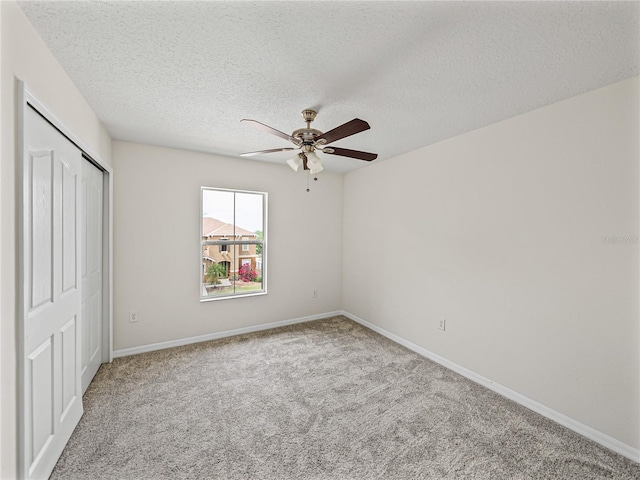 143 Alfani St, Davenport, FL 33896 - unfurnished bedroom featuring carpet, a closet, a textured ceiling, baseboards, and a ceiling fan