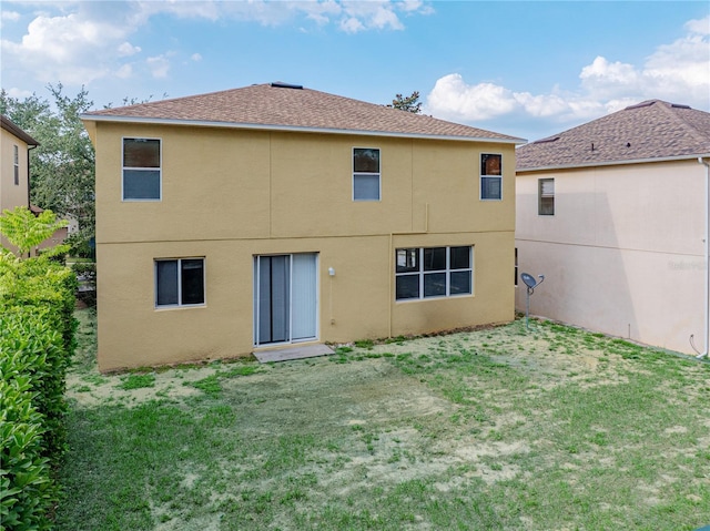 143 Alfani St, Davenport, FL 33896 - back of property featuring stucco siding, a shingled roof, and a lawn