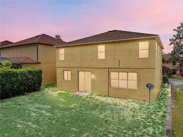 143 Alfani St, Davenport, FL 33896 - back of property at dusk featuring stucco siding and a lawn