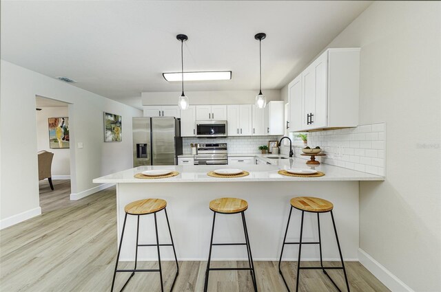 6338 Oak Sq E, Lakeland, FL 33813 - kitchen with stainless steel appliances, tasteful backsplash, a peninsula, light countertops, and white cabinetry