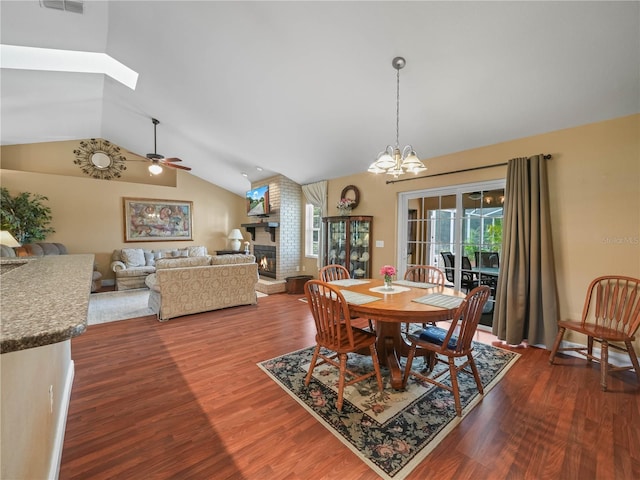 2921 W Socrum Loop Rd, Lakeland, FL 33810 - dining area featuring vaulted ceiling, dark wood-style floors, a brick fireplace, a chandelier, and a ceiling fan