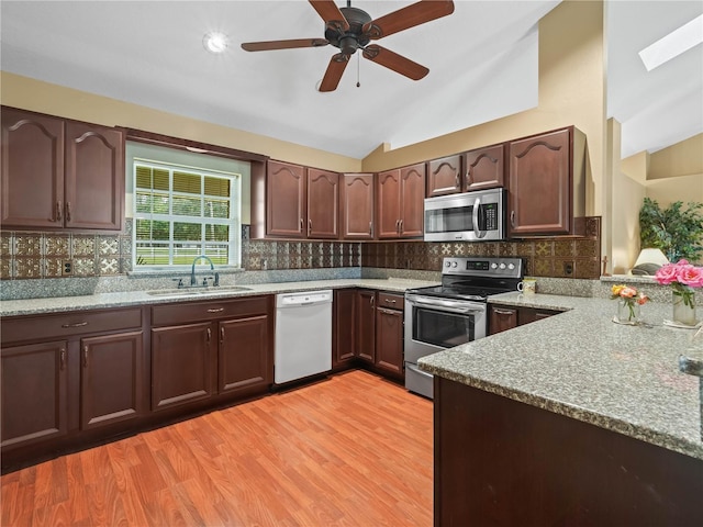2921 W Socrum Loop Rd, Lakeland, FL 33810 - kitchen featuring stainless steel appliances, a sink, light stone countertops, vaulted ceiling, and light wood-style flooring