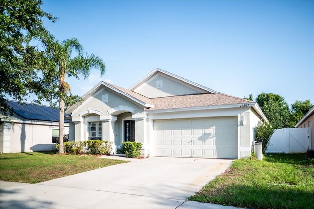 11567 Misty Isle Ln, Riverview, FL 33579 - ranch-style home with stucco siding, an attached garage, driveway, roof with shingles, and a gate