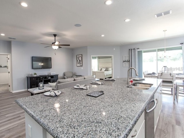 867 Cypress Creek Run, Saint Cloud, FL 34771 - kitchen with a sink, white cabinetry, light wood-style floors, a center island with sink, and a ceiling fan