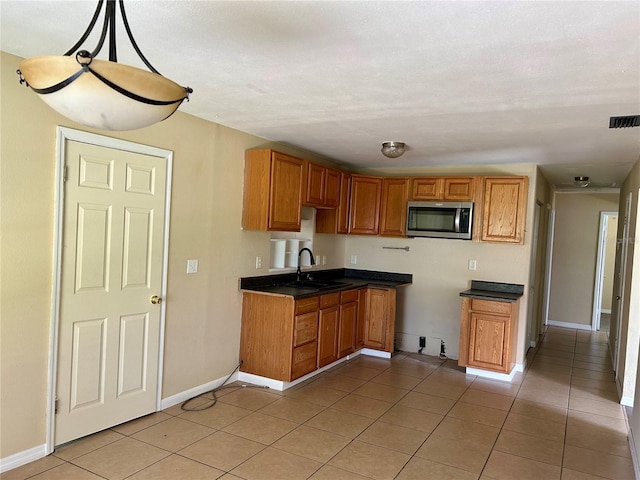 304 Bell St, Wauchula, FL 33873 - kitchen featuring stainless steel microwave, a sink, light tile patterned floors, dark countertops, and baseboards
