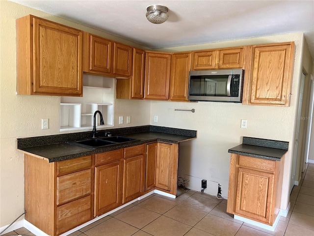 304 Bell St, Wauchula, FL 33873 - kitchen featuring a sink, stainless steel microwave, light tile patterned flooring, and brown cabinets