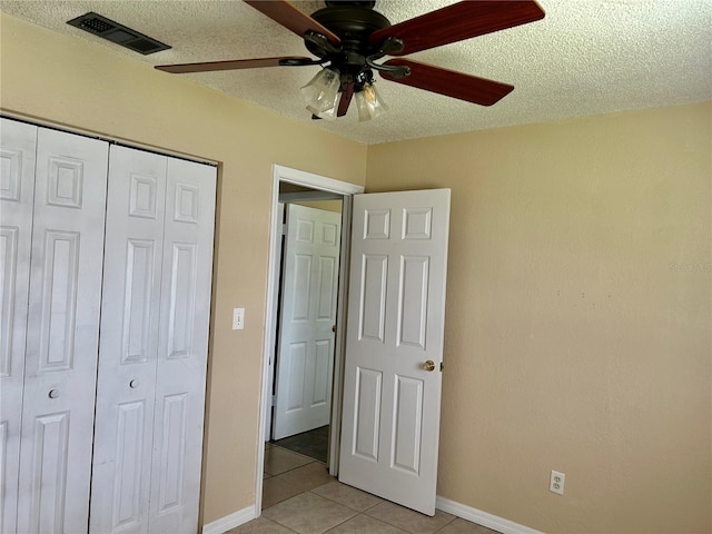 304 Bell St, Wauchula, FL 33873 - unfurnished bedroom featuring light tile patterned flooring, a closet, baseboards, a textured ceiling, and a ceiling fan