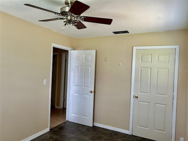 304 Bell St, Wauchula, FL 33873 - unfurnished bedroom with dark tile patterned flooring, baseboards, and ceiling fan