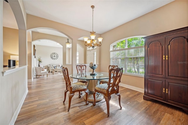 6339 Alamanda Hills Dr, Lakeland, FL 33813 - dining area featuring arched walkways, baseboards, a chandelier, and light wood finished floors