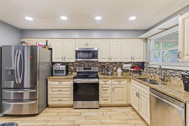 13411 Whitby Rd, Hudson, FL 34667 - kitchen featuring appliances with stainless steel finishes, a sink, a textured ceiling, decorative backsplash, and wood finish floors
