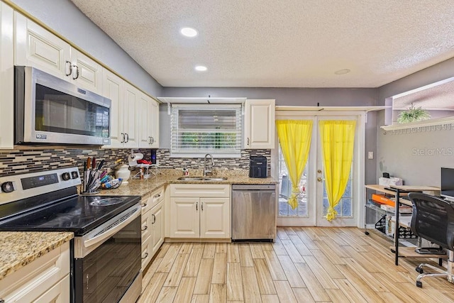 13411 Whitby Rd, Hudson, FL 34667 - kitchen featuring appliances with stainless steel finishes, a sink, a textured ceiling, light wood-style flooring, and tasteful backsplash