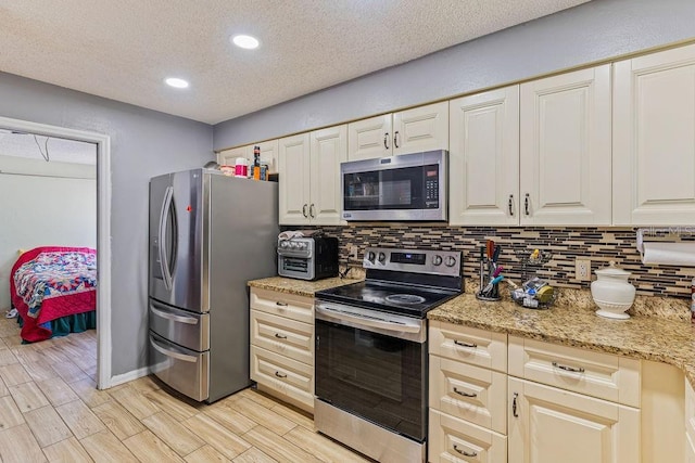 13411 Whitby Rd, Hudson, FL 34667 - kitchen featuring appliances with stainless steel finishes, tasteful backsplash, a textured ceiling, recessed lighting, and light wood-type flooring