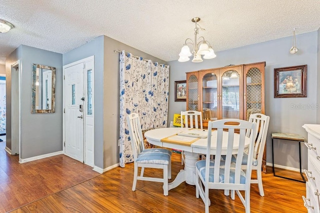 13411 Whitby Rd, Hudson, FL 34667 - dining space with a textured ceiling, wood finished floors, a chandelier, and baseboards