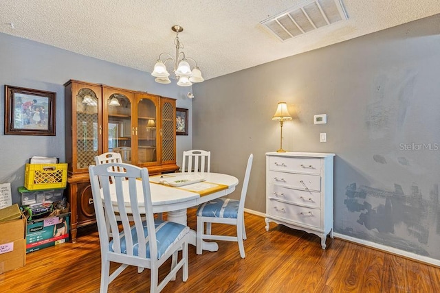 13411 Whitby Rd, Hudson, FL 34667 - dining area featuring a chandelier, wood finished floors, a textured ceiling, and baseboards