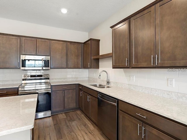 5771 Freshwater Canyon Dr, Saint Cloud, FL 34771 - kitchen with stainless steel appliances, a sink, dark wood-type flooring, dark brown cabinetry, and backsplash
