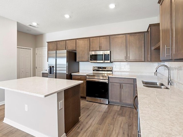 5771 Freshwater Canyon Dr, Saint Cloud, FL 34771 - kitchen with appliances with stainless steel finishes, a sink, wood finished floors, a center island, and recessed lighting