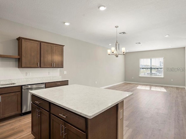 5771 Freshwater Canyon Dr, Saint Cloud, FL 34771 - kitchen featuring stainless steel dishwasher, light wood-style floors, a chandelier, light countertops, and a kitchen island