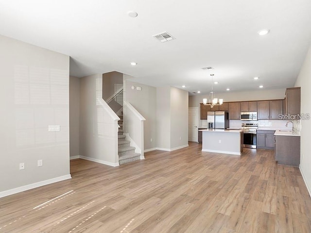5771 Freshwater Canyon Dr, Saint Cloud, FL 34771 - unfurnished living room featuring a chandelier, baseboards, light wood finished floors, recessed lighting, and a sink