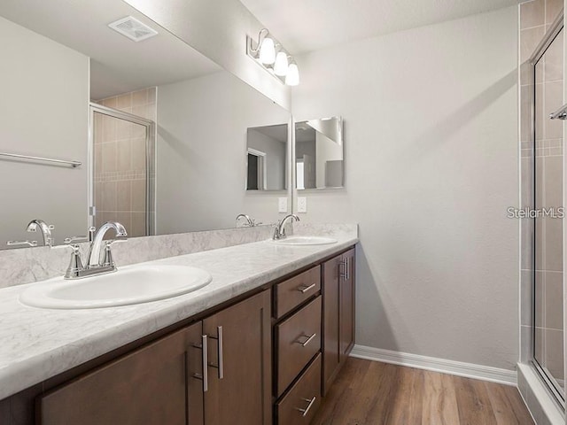 5771 Freshwater Canyon Dr, Saint Cloud, FL 34771 - bathroom with double vanity, wood finished floors, a tile shower, and baseboards